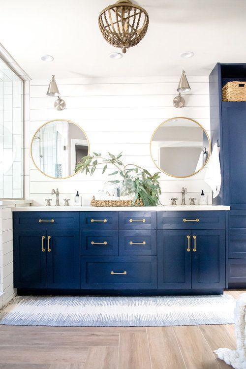 a navy vanity and storage piece, gilded touches and a woven basket plus round mirrors