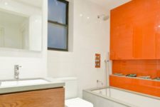 a neutral contemporary bathroom with white tiles, concrete and wood and a statement orange tile wall