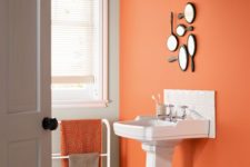 a statement rust wall with a arrangement of hand mirrors and a matching towel to spruce up a monochromatic bathroom