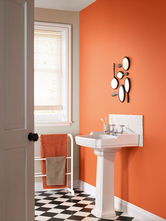 a statement rust wall with a arrangement of hand mirrors and a matching towel to spruce up a monochromatic bathroom