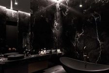 a stunning black masculine bathroom done with black marble, a matte black bathtub and a floating vanity