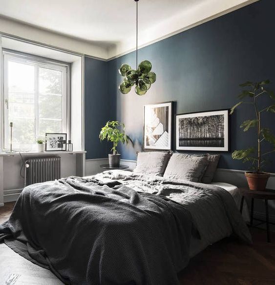 a stylish and relaxing bedroom done in greys and with a navy statement wall, with greenery and green accents