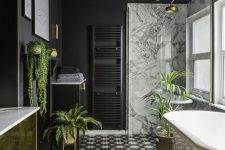 a stylish modern bathroom done with matte black walls, a gold vanity, gold planters and accessories plus cool monochrome tiles