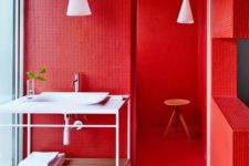 a super bright red bathroom with white appliances and furniture, with white lamps for a bold look