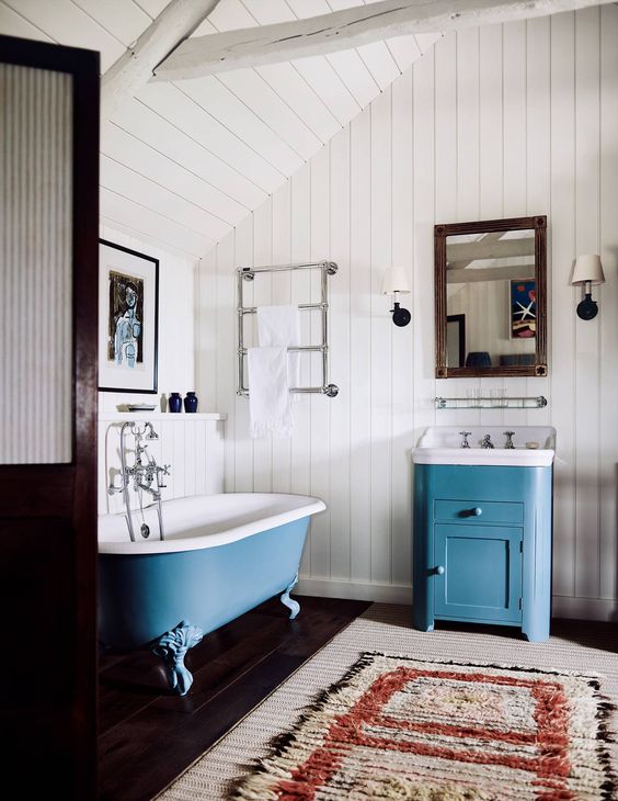 a vanity and a clawfoot bathtub done in blue add a touch of chic color and make the space catchy