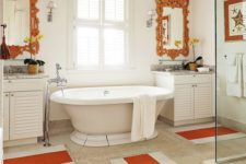 a vintage-inspired bathroom done in neutrals and accented with orange ornate mirrors and striped rugs