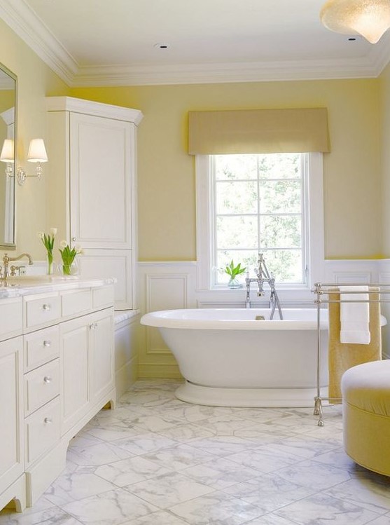 a vintage lemon-infused bathroom with light yellow walls, lemon furniture and textiles and all white around looks warming