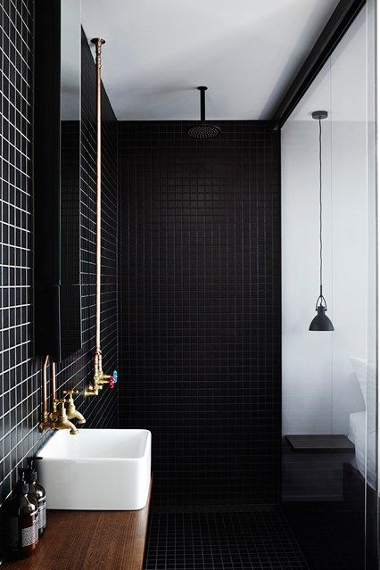 an elegant black and white bathroom with small scale tiles, white appliances, a black pendant lamp and brass vintage fixtures