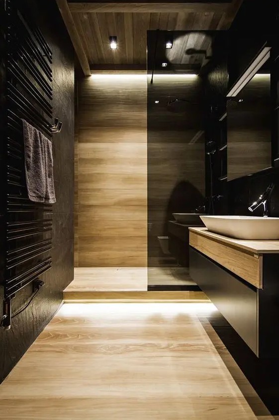 black walls and light-colored wooden wall and floor plus a smoked glass shower wall create a chic modern look