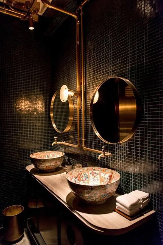 glossy black tiles with contrasting grout make the space refined, and brass touches add chic