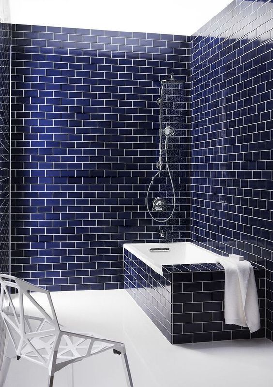 navy subway tiles with white grout and a bathtub clad with the same tiles is a chic and bold contemporary idea