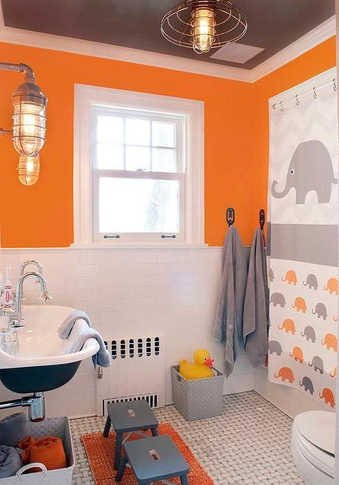 Gray and orange kids bathroom design. Orange walls with gray ceiling and elephant themed curtains.