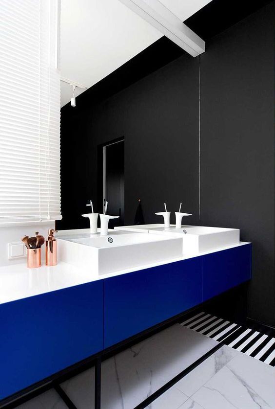 this modern master bathroom features black and white striped flooring, a black wall, and a bright blue vanity