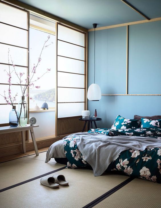 a beautiful zen-like bedroom with traditional Japanese sliding doors, a low bed and wooden furniture, blue walls and a ceiling, floral bedding