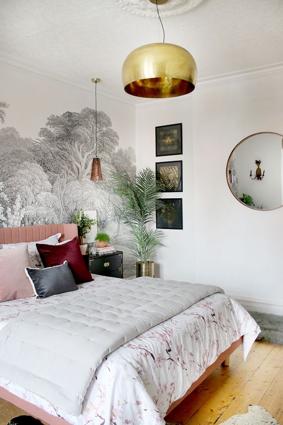 a boho glam bedroom with a botanical wall, touches of gold and brass, bright pillows and a botanical blanket