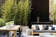 a cool modern terrace with simple furniture, a concrete table, a wooden dining table and metal chairs plus potted greenery