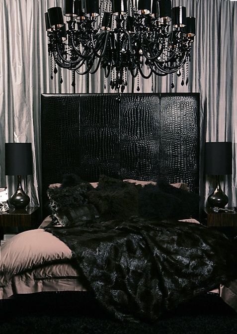 a glam Gothic bedorom with grey curtains, a black leather bed, a statement chandelier and lamps and dusty pink bedding