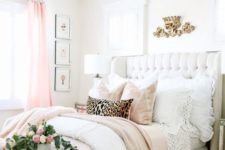a glam pink, gold and neutral bedroom with a mirror bench, a white leather bed, a crystal chandelier and pink touches
