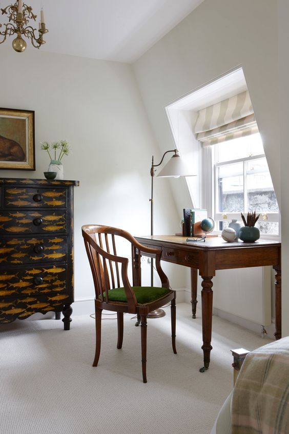 a gorgeous vintage home office nook with a fish print sideboard, a vintage stained desk and a matching stained chair, a floor lamp and a globe