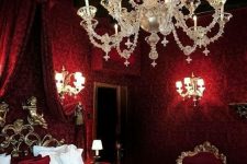 a jaw-dropping vampire bedroom with printed wallpaper, a canopy bed, a refined chandelier and wall sconces