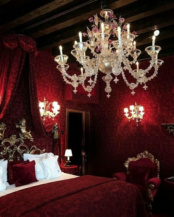a jaw dropping vampire bedroom with printed wallpaper, a canopy bed, a refined chandelier and wall sconces