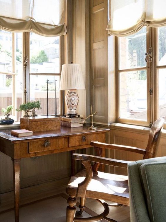 a little and cozy vintage home office nook with a stained desk and a chair, a table lamp and a box for storage is a lovely idea