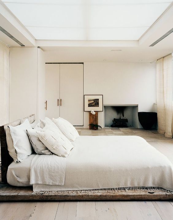 a low-key zen bedroom with a bed placed on a wooden platform, exquisite furniture and a built-in fireplace, a glazed ceiling