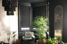 a modern Gothic bedroom with black paneled walls, an abstract print wardrobe, dark furniture, potted plants and a black beaded chandelier