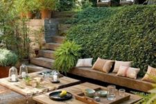 a modern Mediterranean terrace with a built-in bench, modern furniture, wicker ottomans and lots of greenery