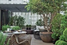 a modern rooftop terrace with potted trees and greenery, wicker chairs and loungers, a concrete table