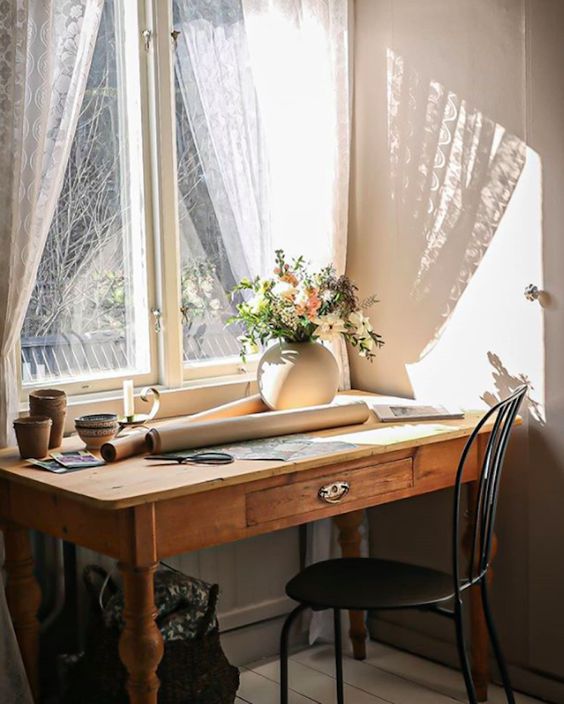 a pretty vintage home office with a wooden desk, a black chair, some blooms in a round vase, some porcelain is amazing