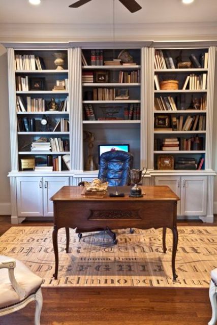 a pretty vintage-infused home office with large bookcases, a black leather chair, a stained vintage desk and a printed rug plus lamps