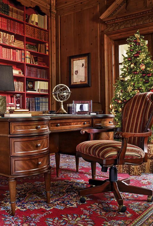 a refined vintage home office fully clad with stained wood, with built-in bookcases, a vintage dark-stained desk, a matching chair with striped upholstery
