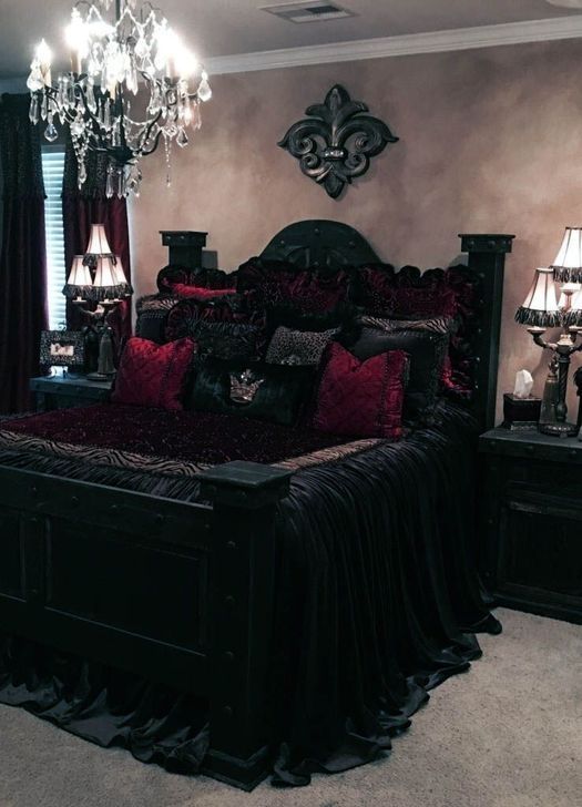 a sophisticated Gothic bedroom with neutral walls, carved wooden black furniture, crimson and black bedding and elegant lights