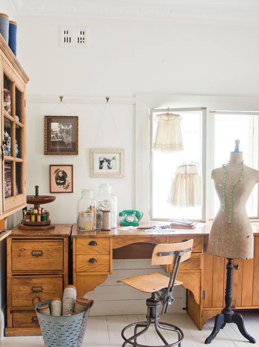 a vintage crafting studio with vintage stained cabinets and a large and heavy desk, an industrial vintage chair, a metal bucket with firewood