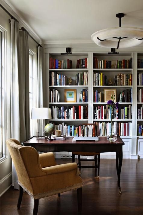 a vintage home office with built-in bookcases, a dark-stained vintage desk, a couple of vintage chairs and some decor
