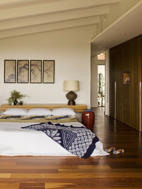 an Asian zen bedroom with a bed on the floor, a floating console at the head, a gallery wall and bright bedding