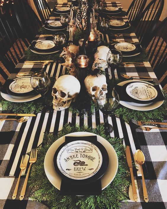 a Halloween tablescape with black and white linens, gold cutlery, skulls, candles and printed plates plus greenery
