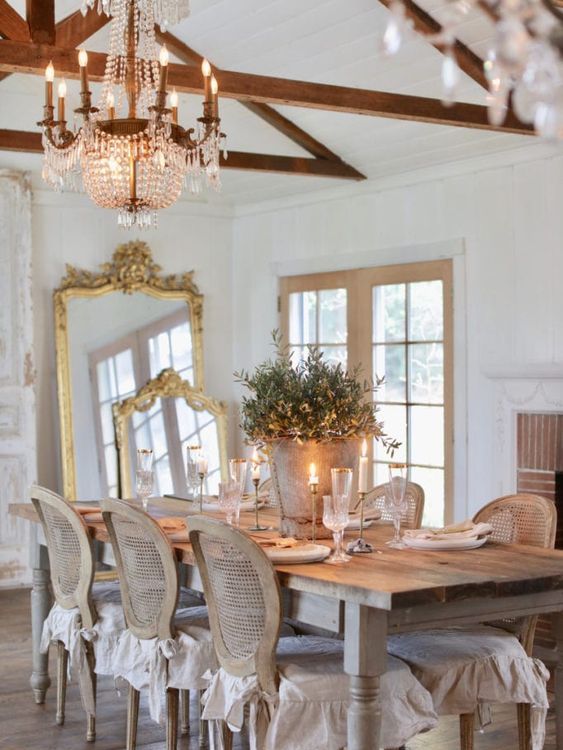 a beautiful antique French chic dining room with a vintage dining table, vintage chairs, crystal chandeliers, mirrors in gilded frames and crystal chandeliers