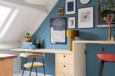 a bright attic home office with a blue accent wall, a desk with two different desktops, upholstered chairs and stools and a chic gallery wall