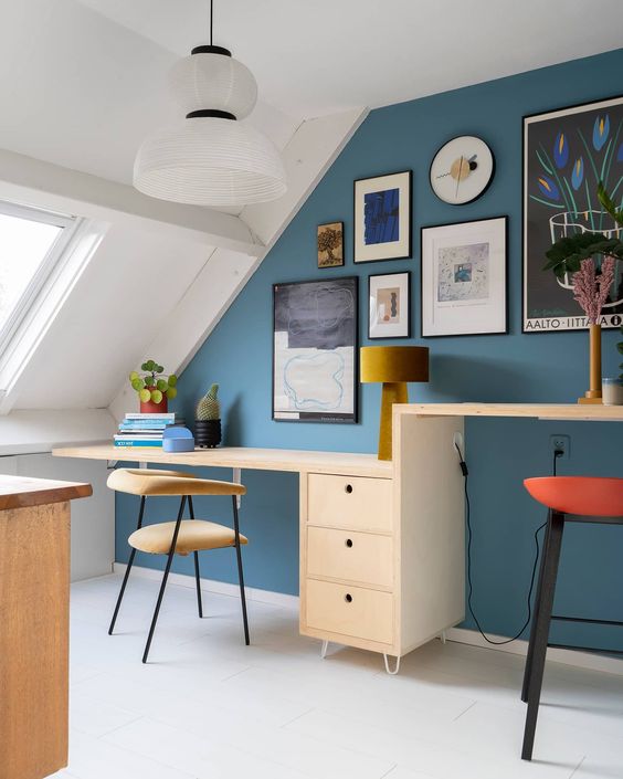 https://www.digsdigs.com/photos/2012/10/a-bright-attic-home-office-with-a-blue-accent-wall-a-desk-with-two-different-desktops-upholstered-chairs-and-stools-and-a-chic-gallery-wall.jpg