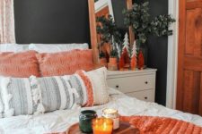 a fall colored bedroom done in black and white, with orange touches and greenery