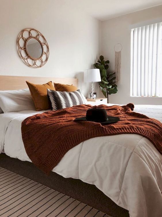 a fall colored bedroom done in neutrals, with rust, mustard and grene touches plus some macrame