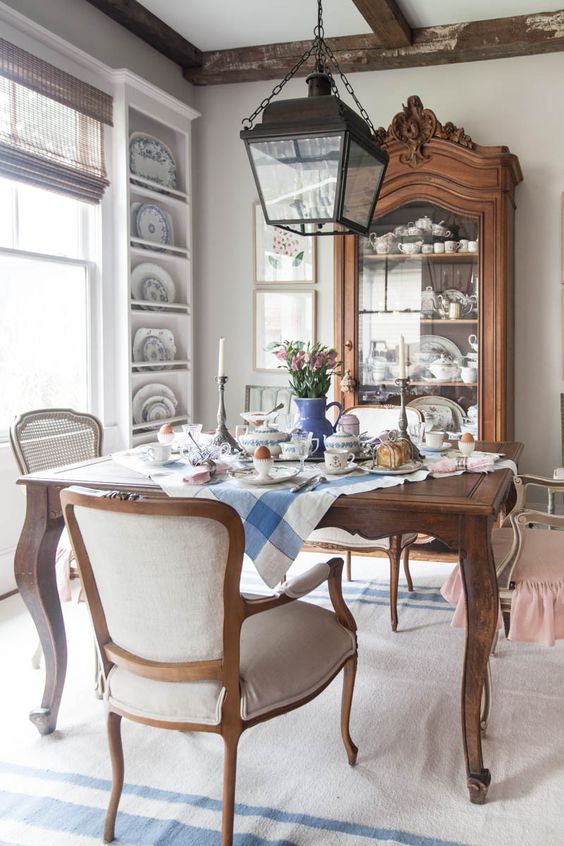 a fantastic French country dining room with wall-mounted shelves, a stained glass cabinet, a stained table and neutral chairs