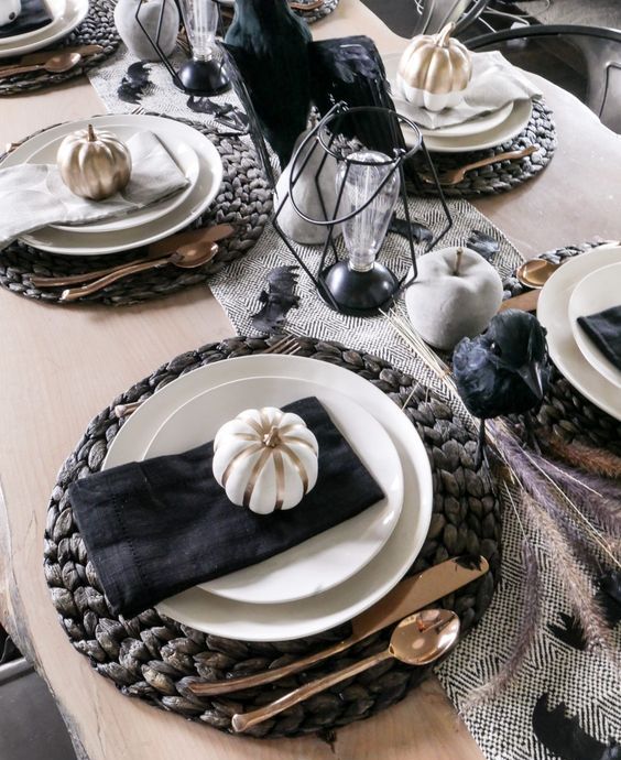 a modern rustic Halloween tablescape with woven placemats, painted apples and pears, candles and bulb lamps