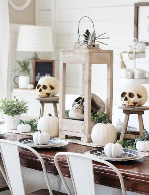 a neutral rustic Halloween tablescape with a woven runner, white pumpkins and skulls, greenery and succulents