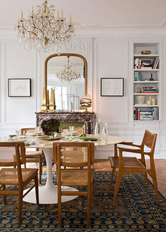 a pretty French dining room with built-in shelves, a fireplace clad with marble, an oval table and stained chairs
