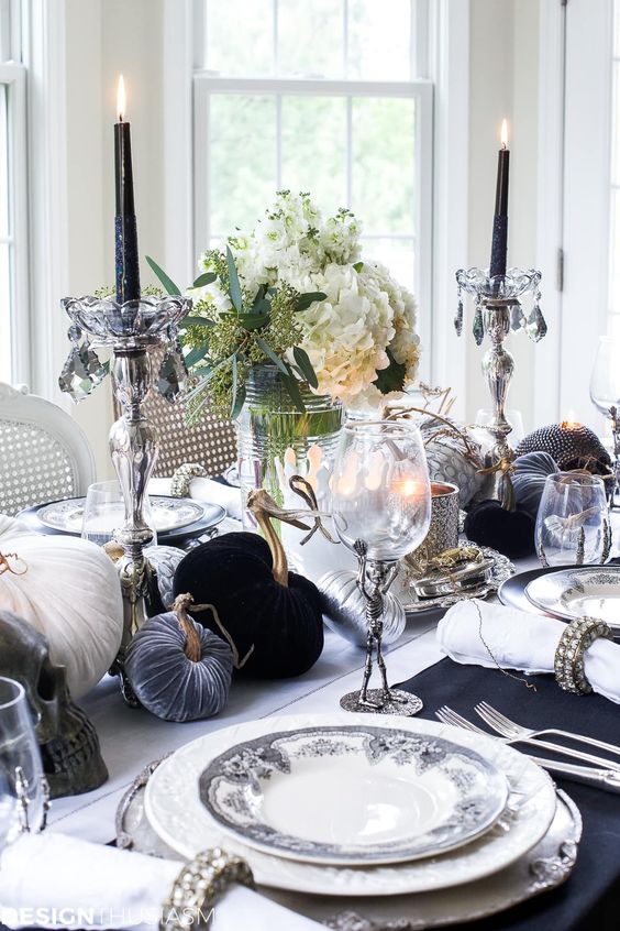 a refined black and white Halloween tablescape with velvet pumpkins, black candles, white blooms, printed plates