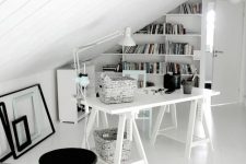 a small Scandinavian home office with a trestle desk, a bookshelf on the wall, some empty frames and a lamp