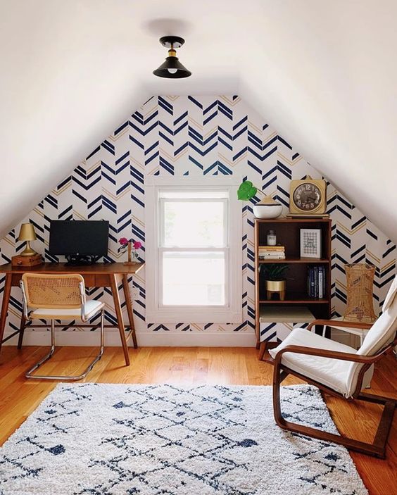 a small and cozy attic home office with a chevron accent wall, a small wooden desk and chairs, a small shelving unit is cool